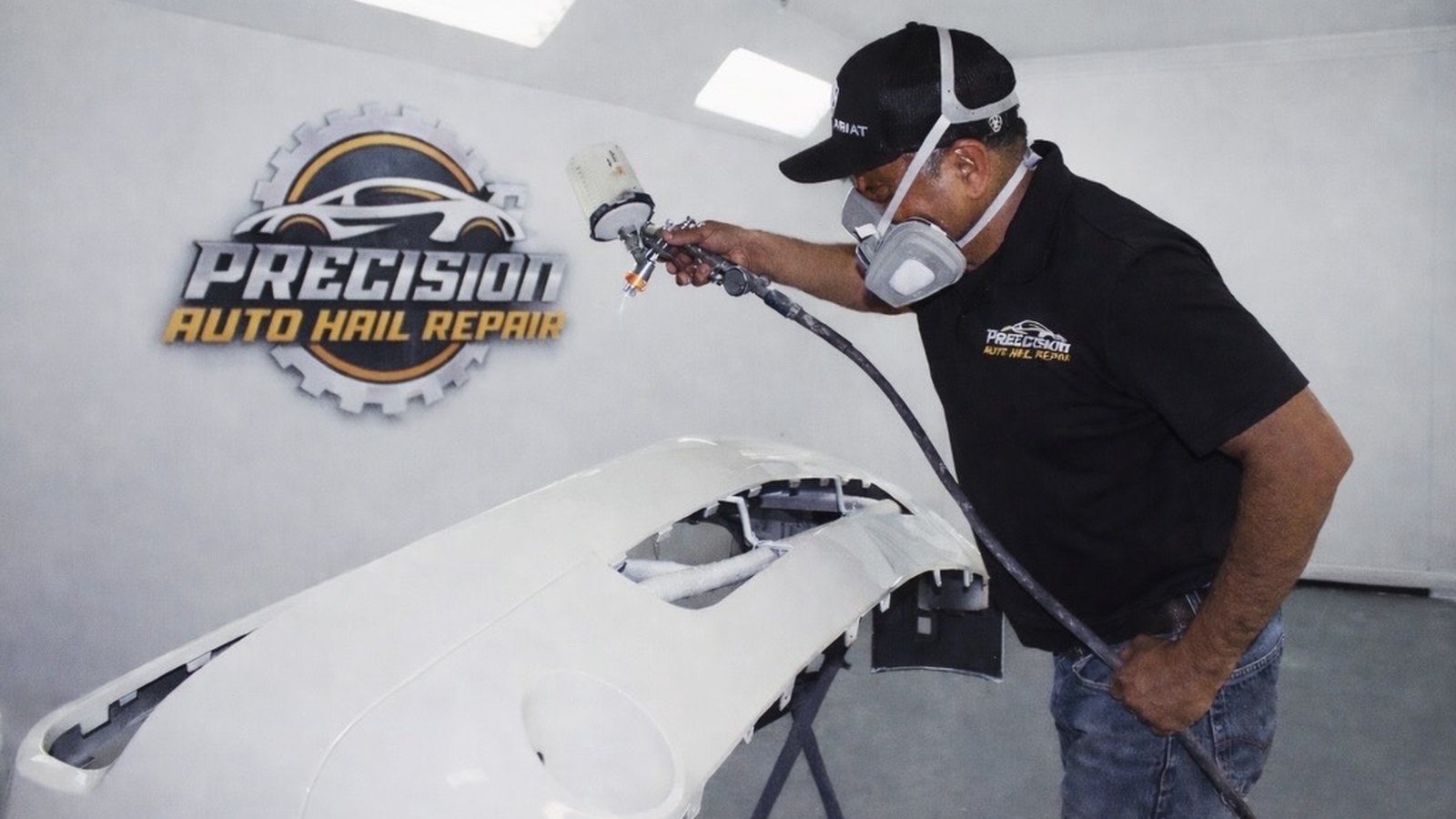 Precision Auto Hail Repair technician refinishing a bumper in the branded paint booth